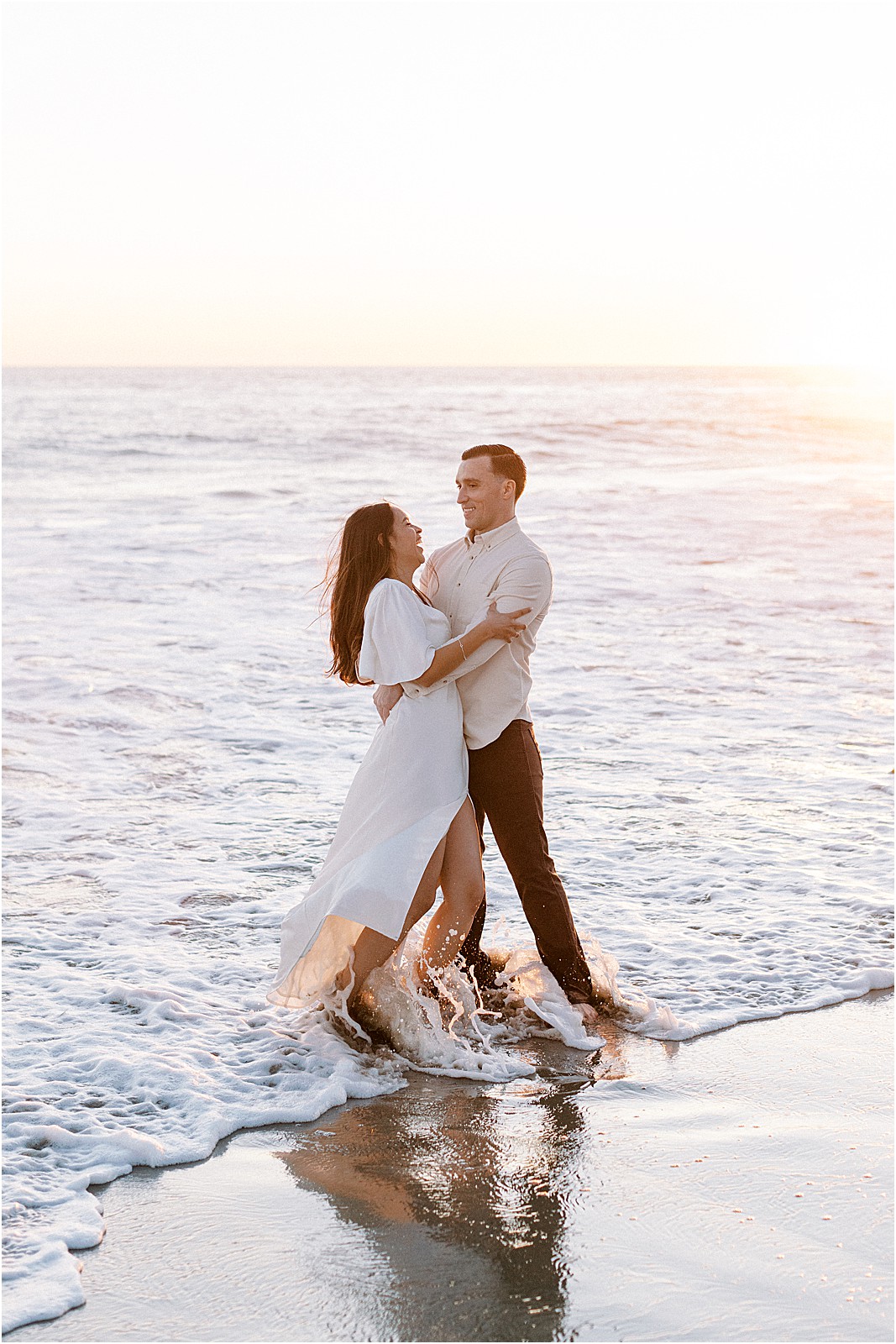 Playful moment with couple laughing in the ocean in Malibu.