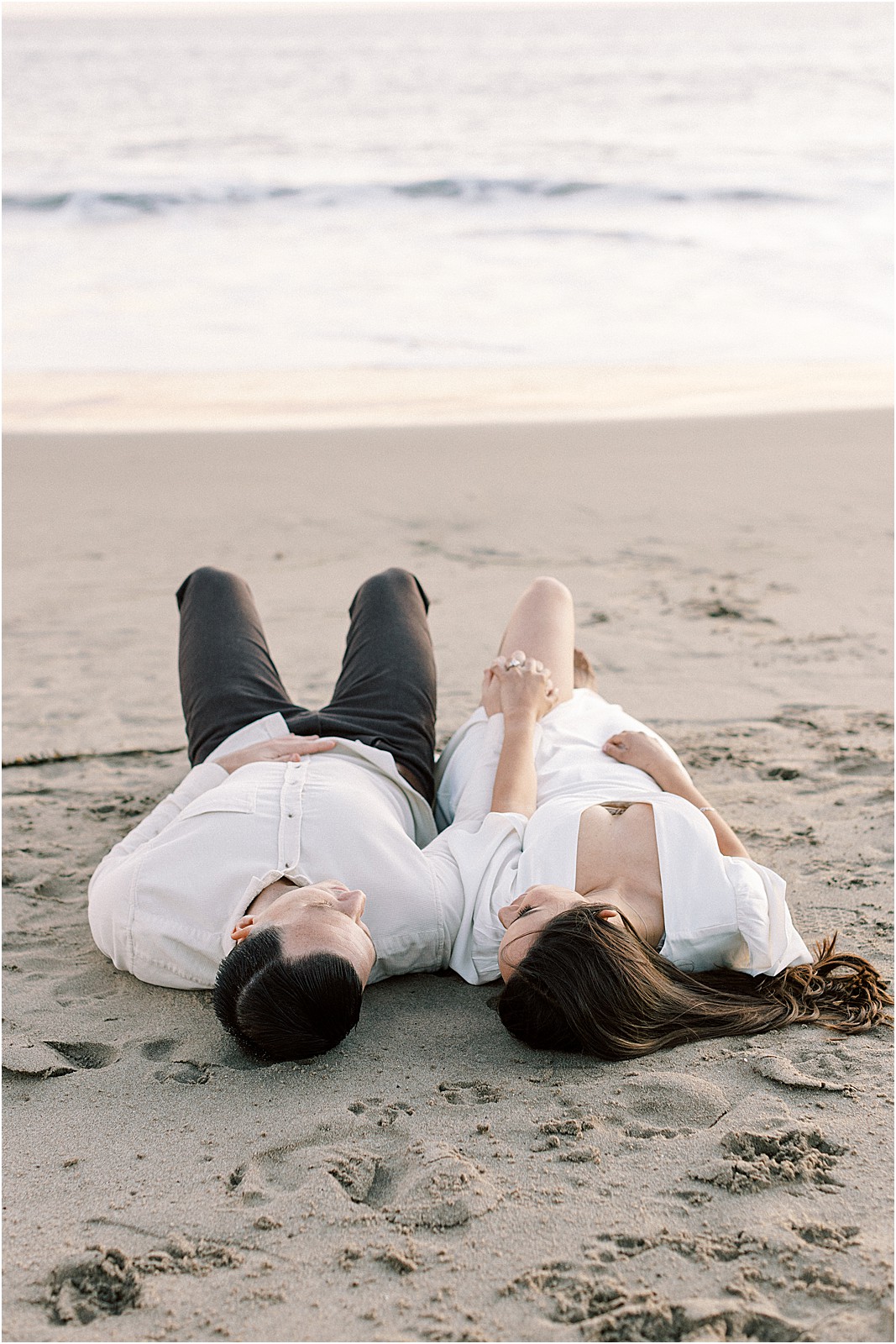 Couple laying together in soft light with ocean in background at Leo Carrillo Beach.