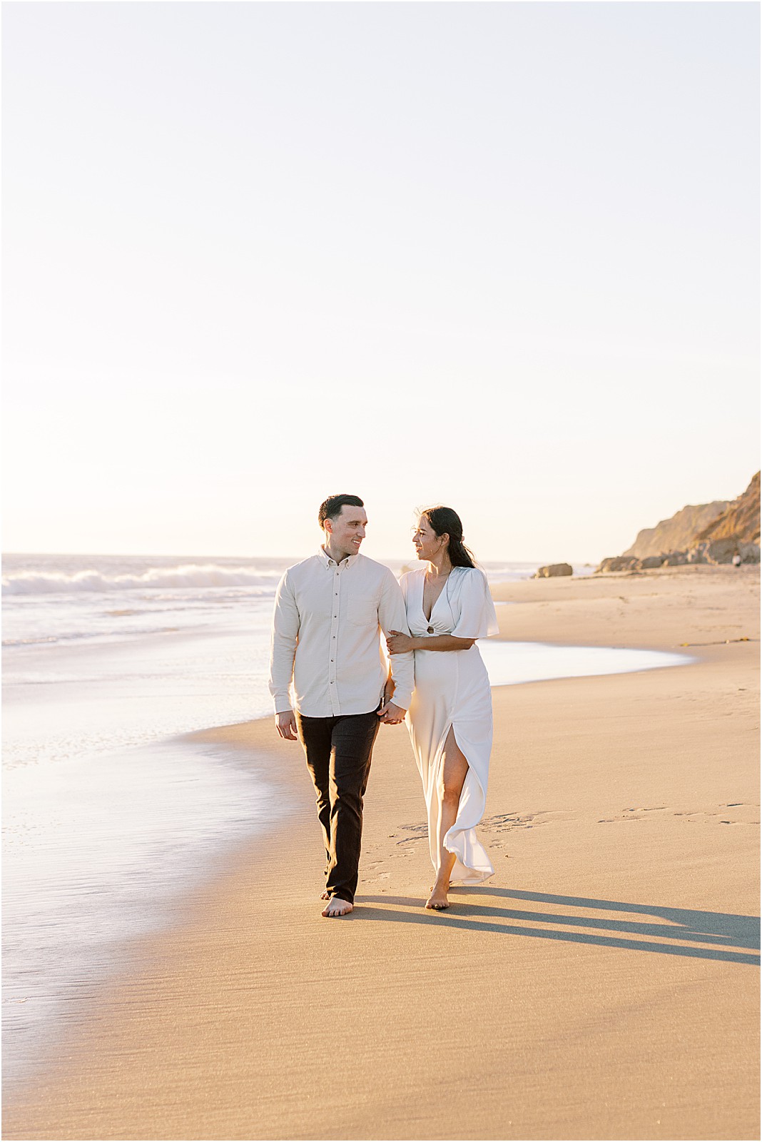 Candid photo of couple walking barefoot along shoreline at Leo Carrillo Beach