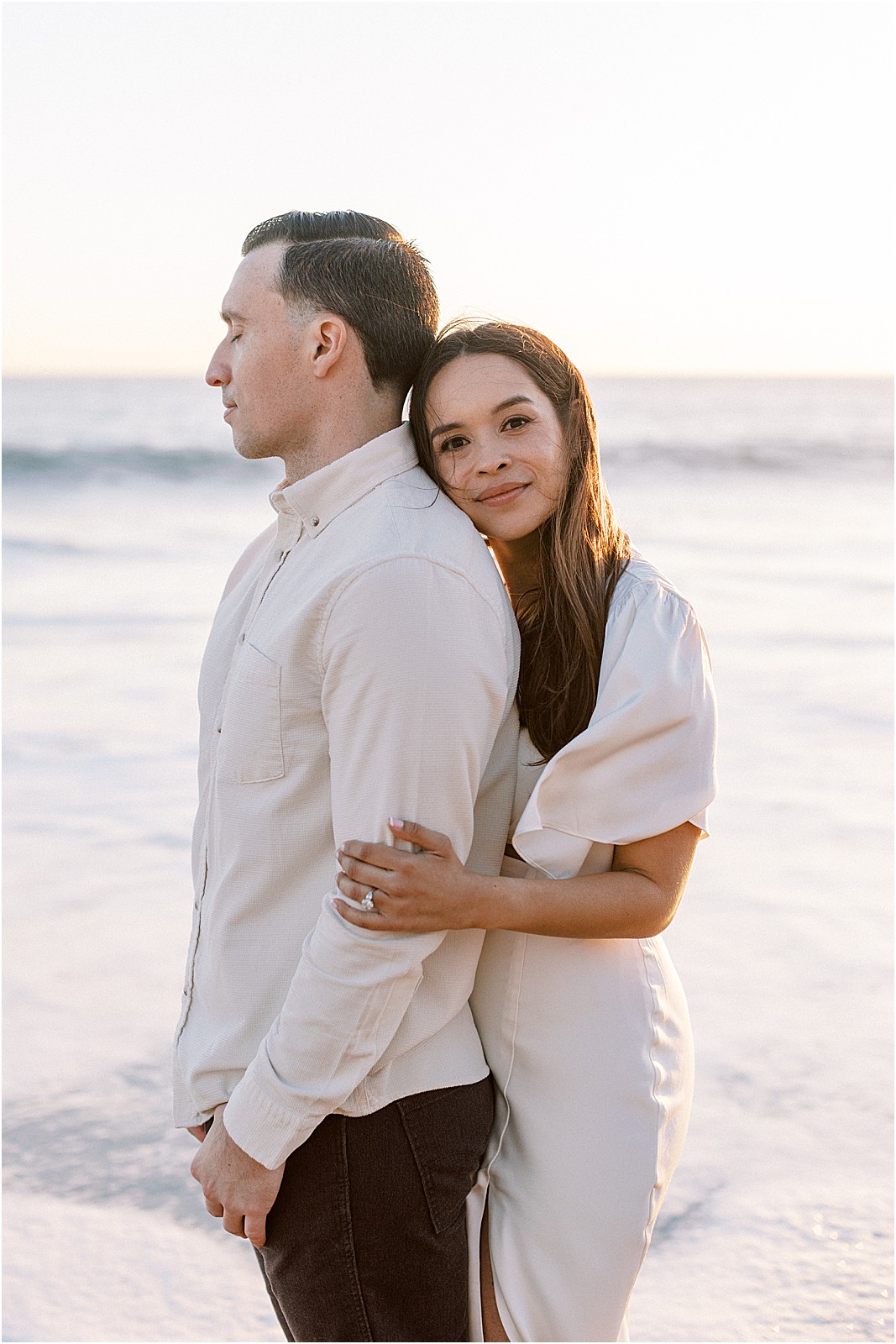 Bride smiling softly at the camera with ocean breeze in her hair during Malibu engagement session