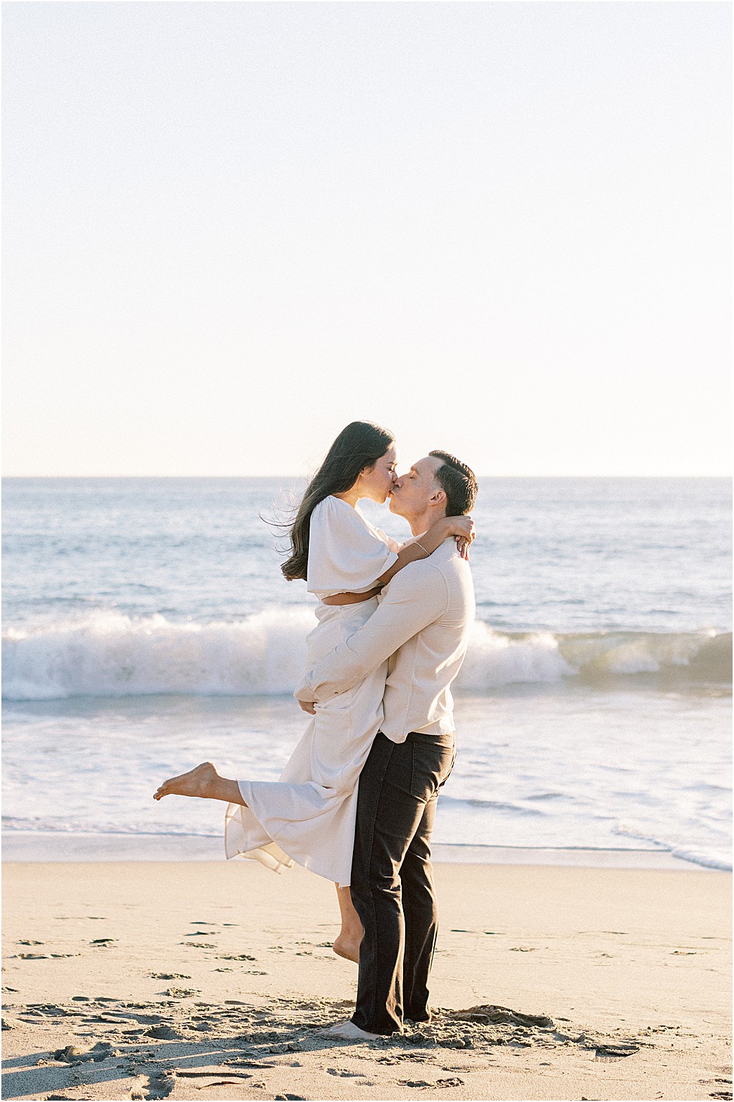 Editorial-style portrait of couple framed by coastal waves in Malibu.