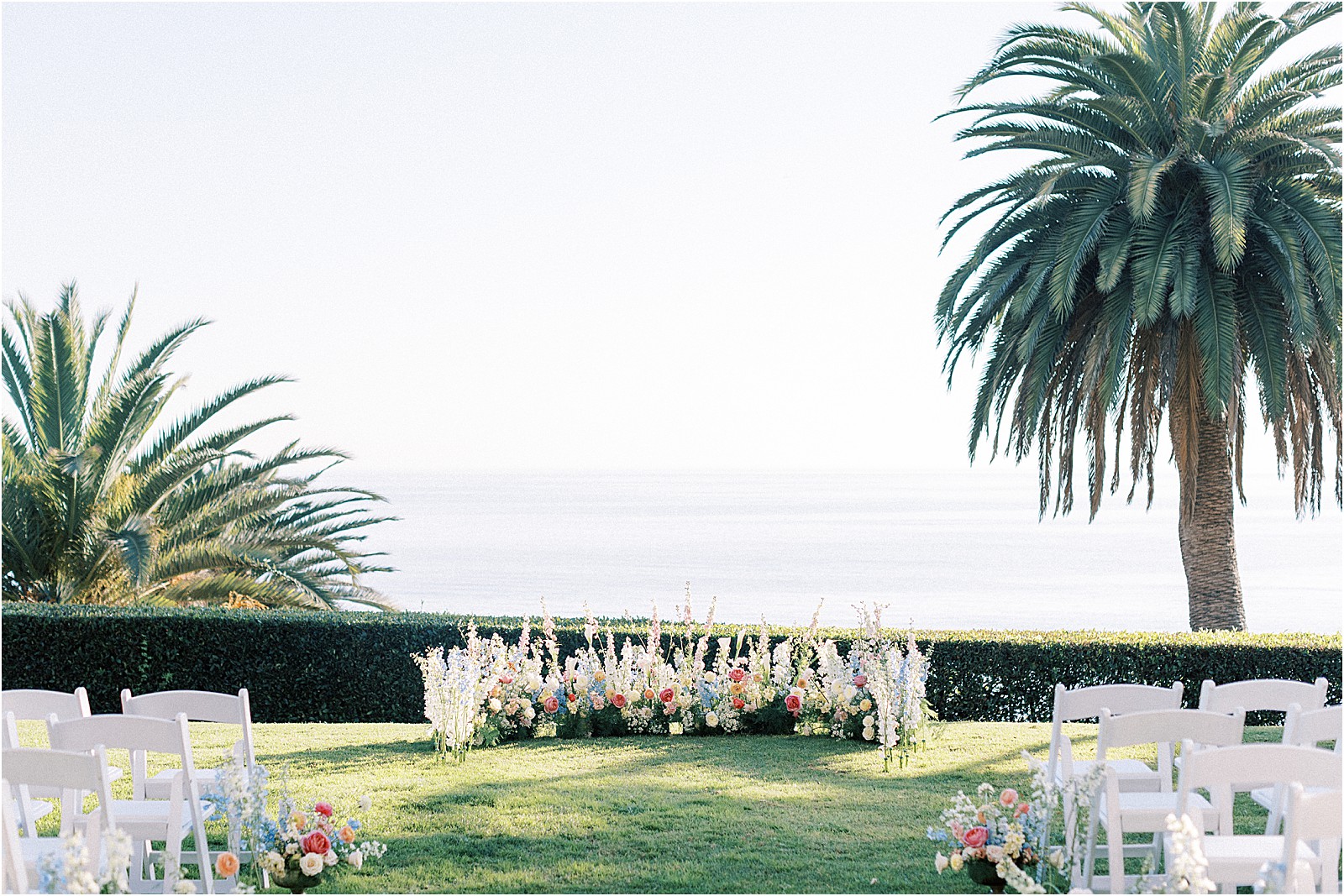 ceremony arch with vibrant florals overlooking the pacific