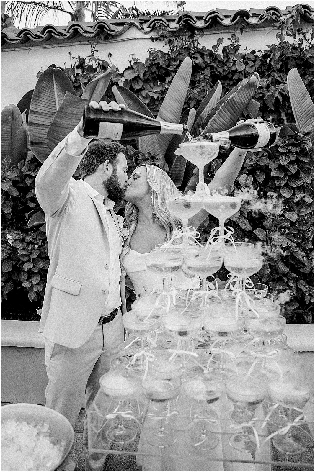 couple kissing while pouring champagne during cocktail hour