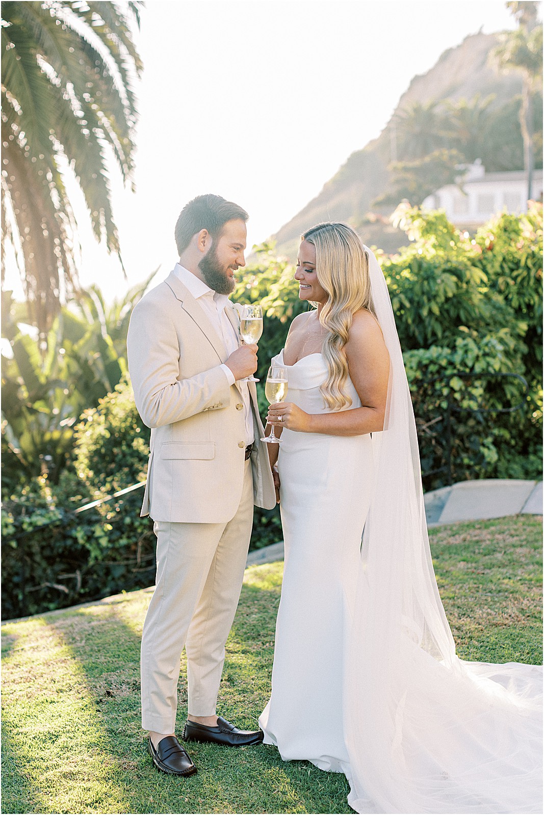 candid moment of the couple laughing and toasting champagne at sunset