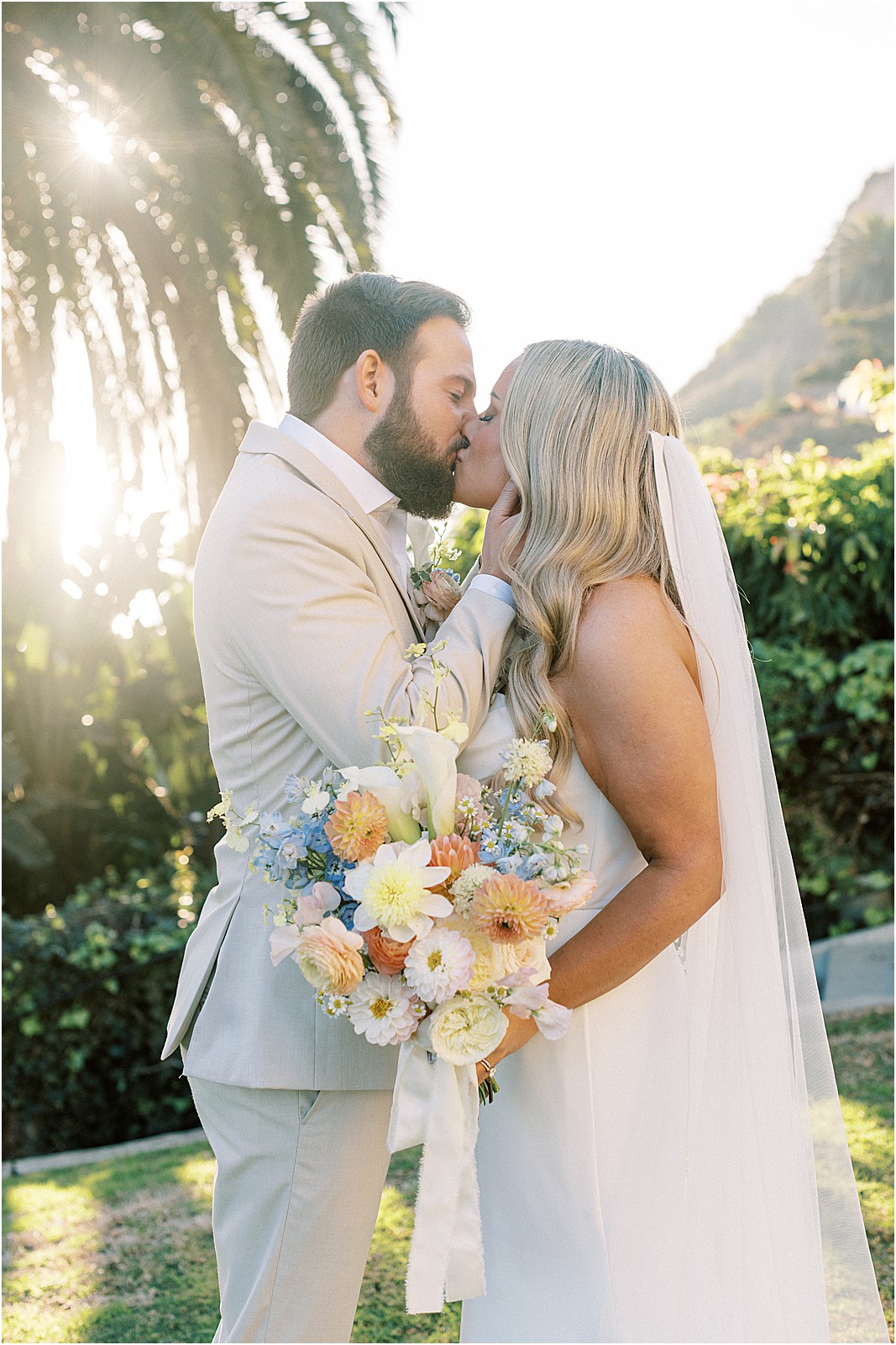 groom holding brides face during a kiss during sunset photos