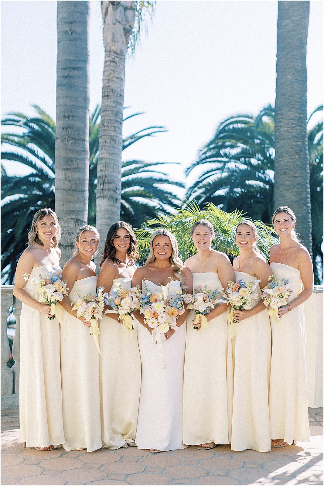 bride surrounded by her bridesmaids smiling for photo