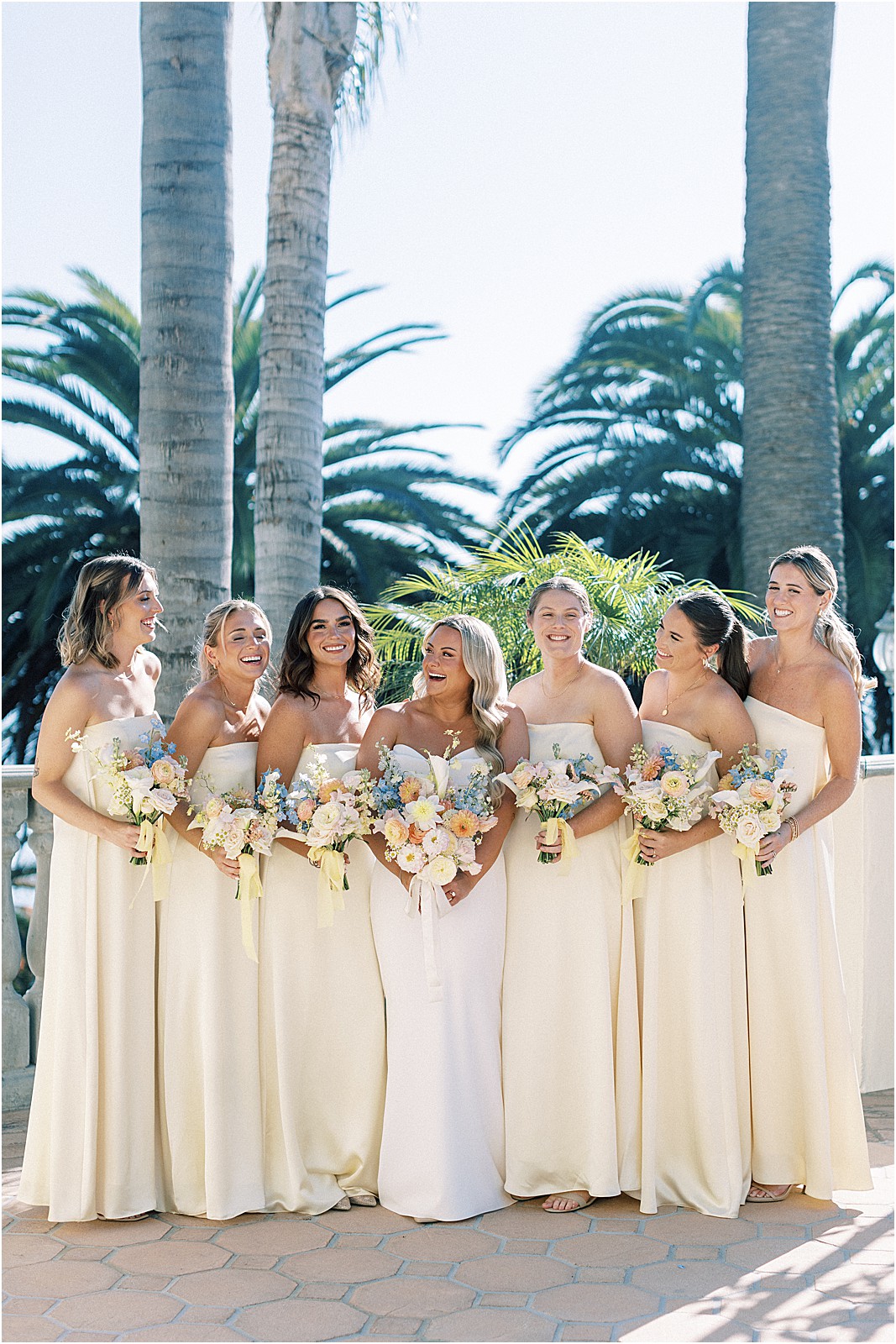 bride surrounded by her bridesmaids in pale yellow dresses