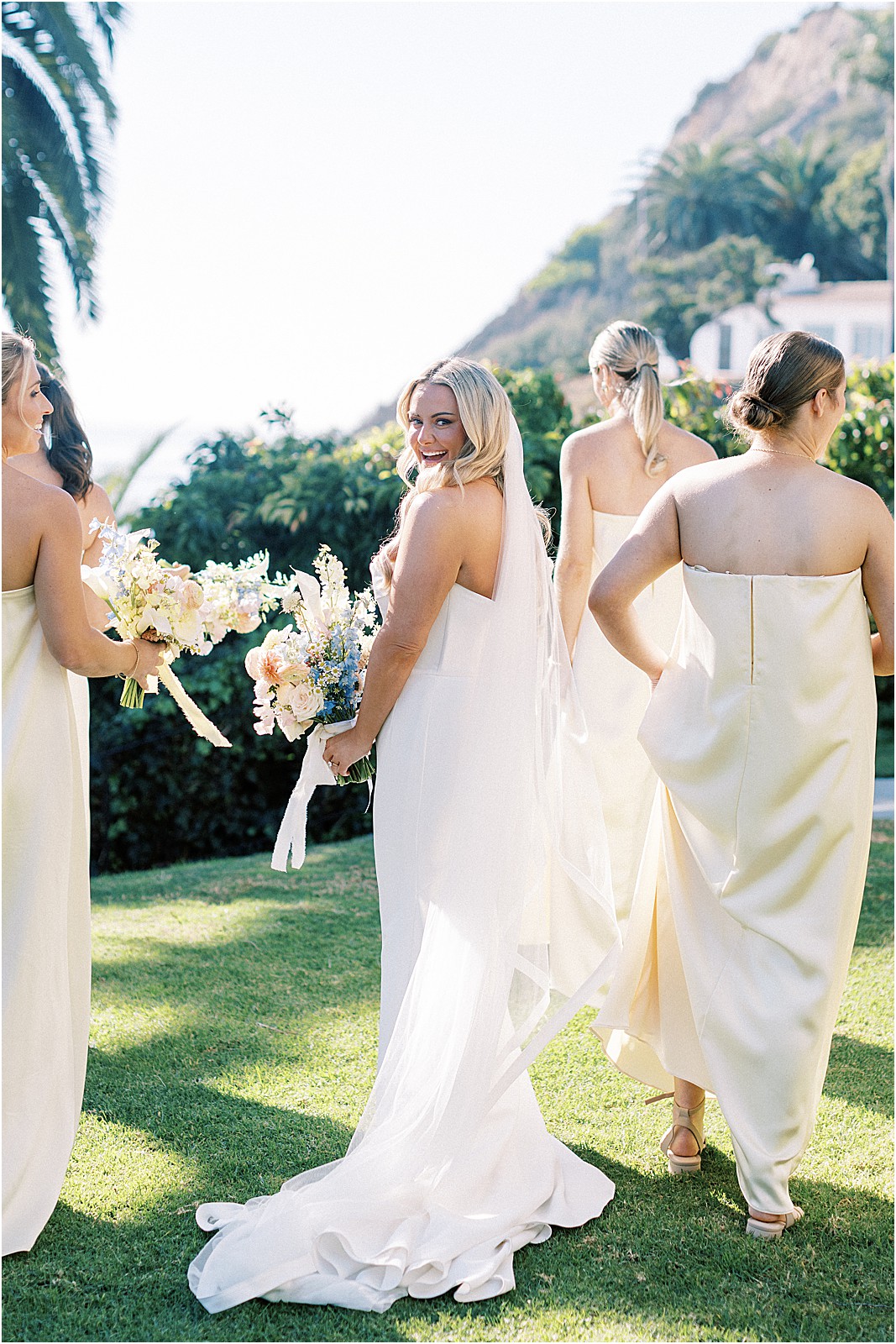 bride looking over her shoulder while walking with bridesmaids